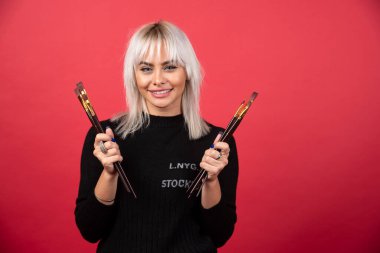 Kırmızı arka planda fırça tutan genç sanatçı kadın. Yüksek kalite fotoğraf