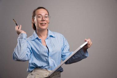 Boş tuval ve gri arka planda fırça kullanan kadın 