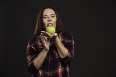 Sonbahar kış koleksiyonu giysileri içinde elinde yeşil bir elma tutan kadın model dehşete düşmüş görünüyor. Yüksek kalite fotoğraf