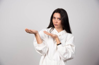 Açık avuç içi gösteren beyaz kapüşonlu genç bir kadın modeli. Yüksek kalite fotoğraf