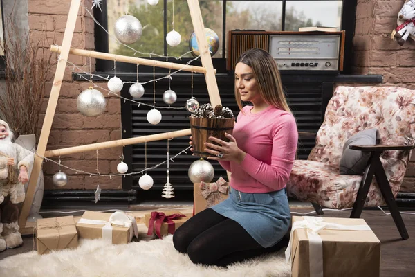 Hermosa Mujer Posando Con Cubo Piñas Sobre Fondo Navideño Foto — Foto de Stock