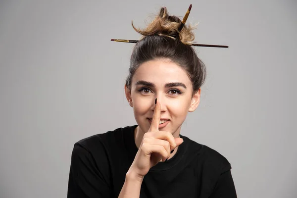 Young woman with messy bun making gesture on gray background. High quality photo