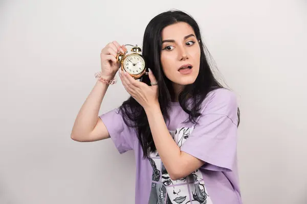 Mujer Joven Escuchando Tictac Reloj Sobre Fondo Blanco —  Fotos de Stock