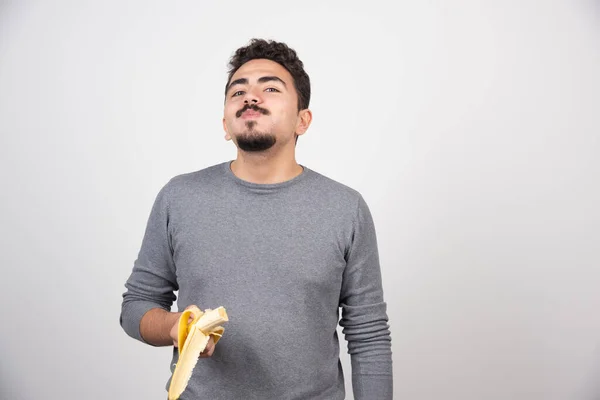 Jovem Sorrindo Comendo Uma Banana Sobre Uma Parede Branca Foto — Fotografia de Stock