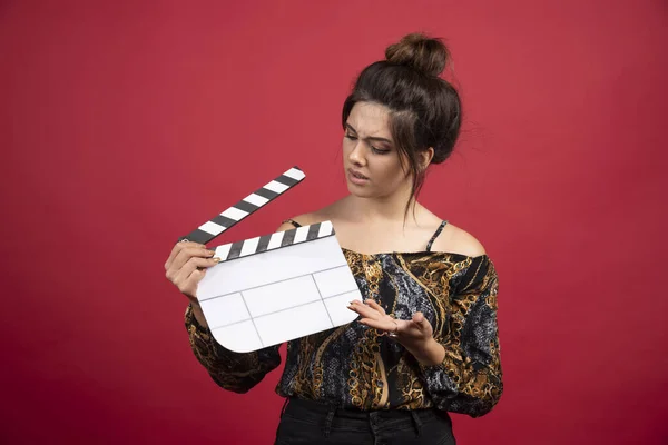 Brunette Meisje Met Een Blanco Klapbord Voor Filmproductie Rode Achtergrond — Stockfoto