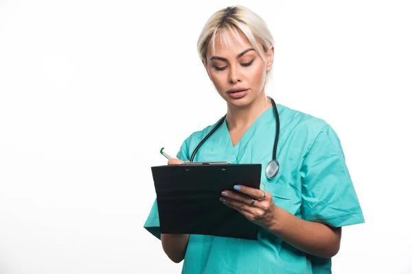 白い背景にペンでクリップボードに何かを書いている女性医師 高品質の写真 — ストック写真