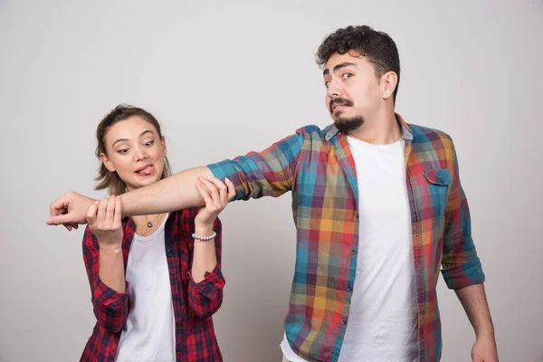 Giovane Donna Che Cerca Mordere Mano Uomo Muro Grigio Foto — Foto Stock