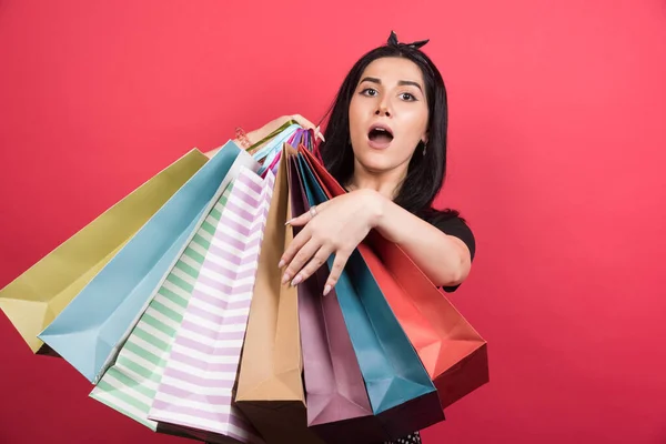 Geschokte Vrouw Met Veel Van Tassen Rode Achtergrond — Stockfoto