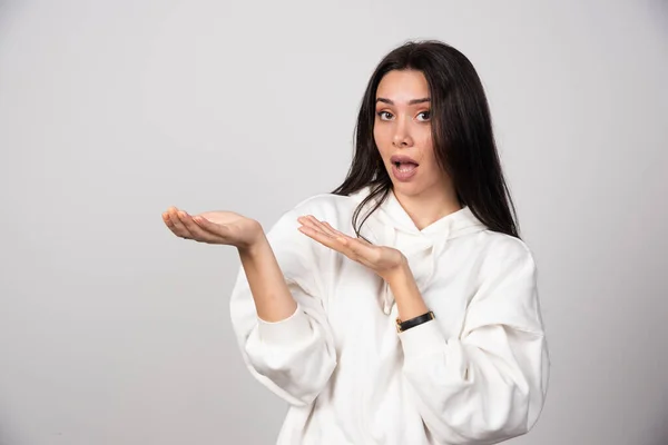 Obraz Młodej Modelki Białej Bluzie Kapturem Pokazującej Otwartą Dłoń Wysokiej — Zdjęcie stockowe