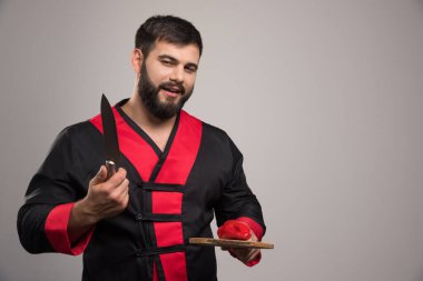 Elinde kırmızı biber ve bıçakla tahta tahta tutan genç adam. Yüksek kalite fotoğraf