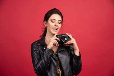 Siyah deri ceketli, elinde profesyonel kamerasıyla güzel fotoğraflar çeken havalı bir kız. Yüksek kalite fotoğraf