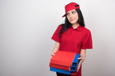 Genç teslimatçı kadın elinde beyaz arka planda üç kutu pizza tutuyor. Yüksek kalite fotoğraf