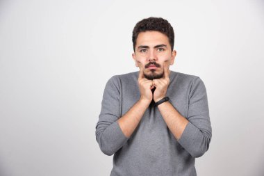 Elleri beyaz duvarın üzerinde poz veren genç bir adam. Yüksek kalite fotoğraf