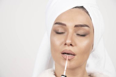 Bornozlu genç bir kadın ruj sürüyor. Yüksek kalite fotoğraf