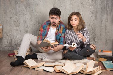 Yerde otururken kitap okuyan güzel bir çift resmi. Yüksek kalite fotoğraf
