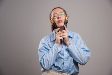 Kadın sanatçı, gri arka planda yüzünün yakınında fırça boyası tutuyor.