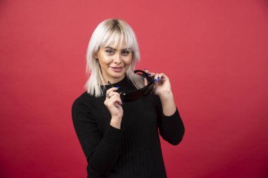 Kırmızı arka planda siyah gözlük takan kadın portresi. Yüksek kalite fotoğraf.