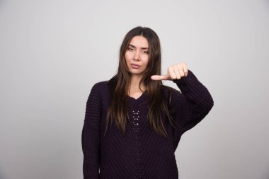 Genç bir kadın baş parmağıyla işaret ediyor ve yan tarafa doğru gösteriyor. Yüksek kalite fotoğraf