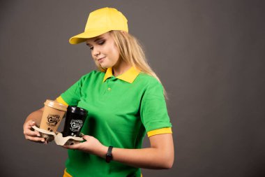 Teslimatçı kadın arka planda kahve fincanlarına bakıyor. Yüksek kalite fotoğraf