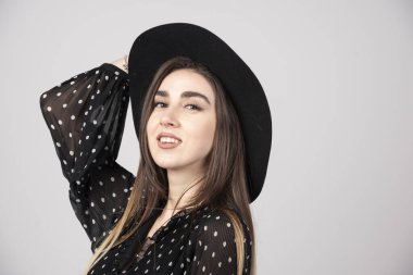 Kafasında şapka tutan siyah elbiseli genç bir kadın. Yüksek kalite fotoğraf