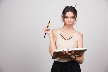 Elinde tuval ve gri arka planda fırça tutan kadın ressam. Yüksek kalite fotoğraf