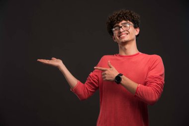 Kıvırcık saçlı genç bir manken bir şeylerin reklamını yapıyor. Yüksek kalite fotoğraf