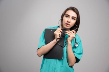 Kadın doktor gri arka planda steteskop kullanıyor. Yüksek kalite fotoğraf