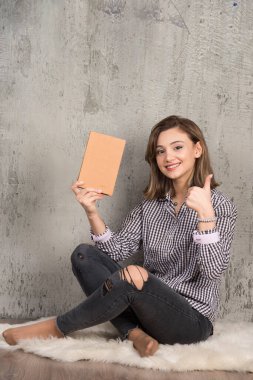 Turuncu kitabı olan kız öğrenci onaylıyor. Yüksek kalite fotoğraf