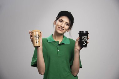 Lezzetli kahve ile poz veren yeşil üniformalı teslimatçı kadın. Yüksek kalite fotoğraf