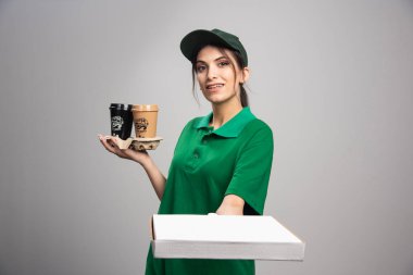 Teslimatçı kadın gri arka plandaki müşteriye pizza kutusu veriyor. Yüksek kalite fotoğraf