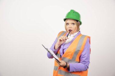 Beyaz arka planda yeşil miğferi ve panosu olan genç bir kadın müteahhit. Yüksek kalite fotoğraf