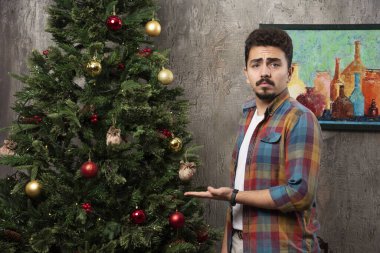 Mutlu adam Noel ağacını elleriyle işaret ediyor. Yüksek kalite fotoğraf