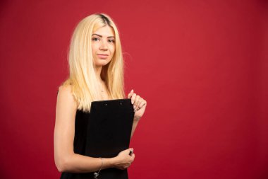 Elinde pano olan ve kırmızı arka planda duran kadın bir çalışan. Yüksek kalite fotoğraf