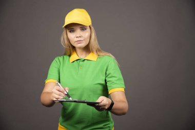 Kalem ve not panosu olan genç bir kadın kurye. Yüksek kalite fotoğraf