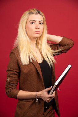 Kırmızı arka planda duran defterli bir bayan çalışan. Yüksek kalite fotoğraf