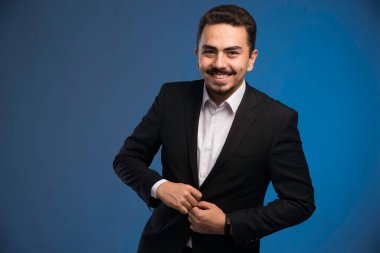 Siyah takım elbiseli iş adamı ceketinin düğmelerini ilikliyor. Yüksek kalite fotoğraf