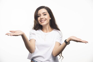 Beyaz tişörtlü dalgalı saçlı kadın ellerini gösteriyor. Yüksek kalite fotoğraf