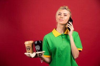 Teslimatçı kadın konuşurken elinde iki fincan kahve tutuyor. Yüksek kalite fotoğraf