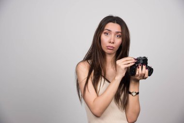 Gri arka planda kamerayla poz veren genç bir kadın. Yüksek kalite fotoğraf