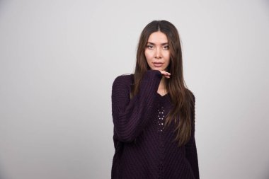 Gri arka planda duran mor kazaklı genç bir kadın. Yüksek kalite fotoğraf