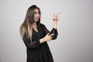 Gri arkaplandaki bir şeyi işaret eden kadın portresi. Yüksek kalite fotoğraf