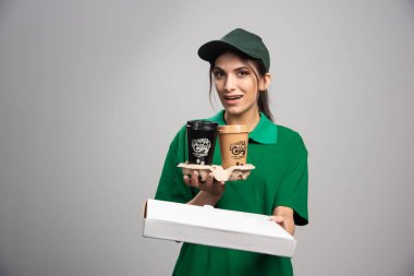 Teslimatçı kadın gri arka plandaki müşteriye pizza kutusu veriyor. Yüksek kalite fotoğraf