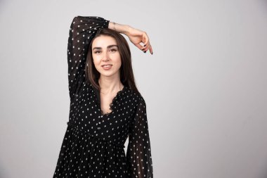 Siyah elbiseli kadın gri arka planda poz veriyor. Yüksek kalite fotoğraf