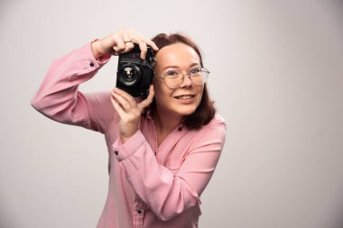 Beyaz arka planda kamerayla fotoğraf çeken bir kadın. Yüksek kalite fotoğraf