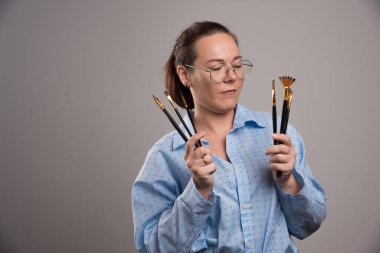 Kadın sanatçı gri arka planda boya fırçaları tutuyor. Yüksek kalite fotoğraf