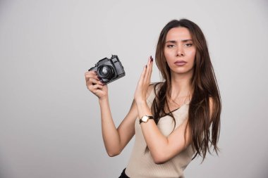Gri arka plandaki kamerayı reddeden ciddi bir kadın. Yüksek kalite fotoğraf