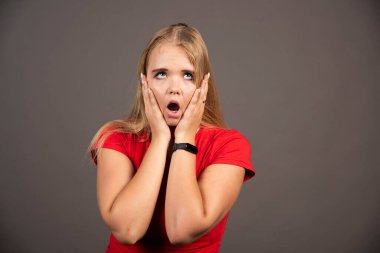 Kırmızı gömlekli genç bir kadın koyu arka planda poz veriyor. Yüksek kalite fotoğraf