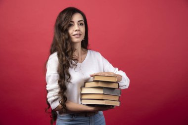 Kırmızı arka planda kitap taşıyan güzel bir kadın. Yüksek kalite fotoğraf