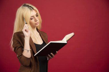 İş kadınının kırmızı arka planda belgeler okuduğunu düşünüyorum. Yüksek kalite fotoğraf
