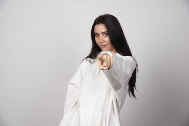 Beyaz gri arka planda kamerayı gösteren genç ve güzel bir kadın. Yüksek kalite fotoğraf